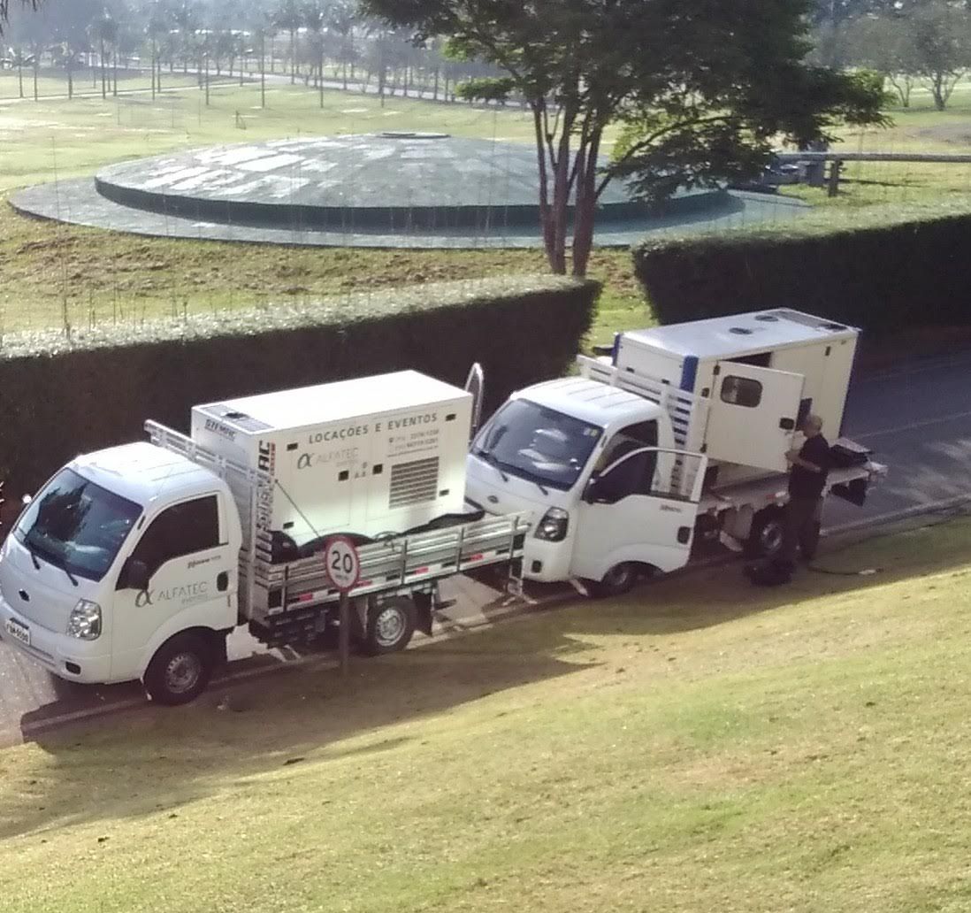 Dois caminhões da Alfatec com geradores em gramado de parque para evento ao ar livre